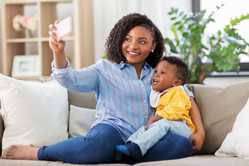 family, technology and motherhood concept - happy smiling young african american mother with little...