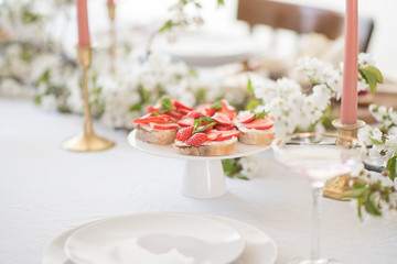 Laying and decor of the wedding banquet table. Plates, knives, forks, glasses, plates, flowers, snacks and fruit. The main thing in the details.