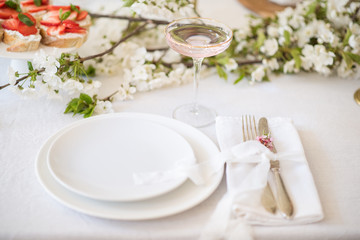 Laying and decor of the wedding banquet table. Plates, knives, forks, glasses, plates, flowers, snacks and fruit. The main thing in the details.