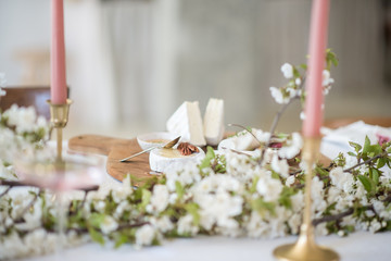 Laying and decor of the wedding banquet table. Plates, knives, forks, glasses, plates, flowers, snacks and fruit. The main thing in the details.