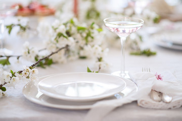 Laying and decor of the wedding banquet table. Plates, knives, forks, glasses, plates, flowers, snacks and fruit. The main thing in the details.