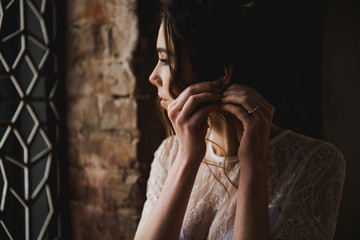 The bride puts on an earring. Portrait of a beautiful bride. Classical wedding.