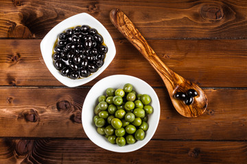 Green and black olives on rustic board