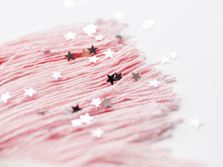 Pink mane and tail of cute unicorn made of threads. Crocheted hand made toy on white background with silver stars confetti. Trendy creature, symbol of magic and miracles.