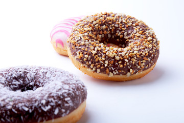 Assorted doughnuts in the glaze, colorful sprinkles and nuts on a white background.