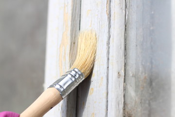 hand in a lilac glove holding a paint brush against the background of an unpainted window