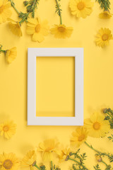 Obraz premium Flowers composition. Chamomile flowers with photo frame on yellow background. Spring, summer concept. Flat lay, top view, copy space