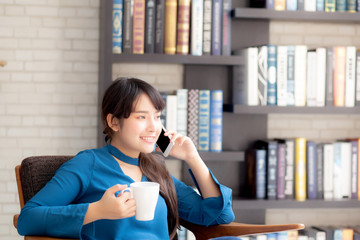 Beautiful portrait young asian woman smiling using mobile smart phone talking enjoy and drink coffee with relax, girl sitting on chair at living room, communication concept.