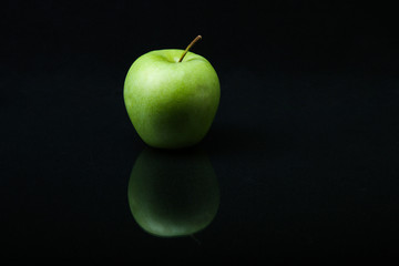 green apple on a black background with reflection. fruit isolated on black background