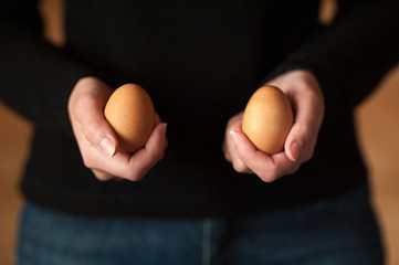 Woman hand holding two brown chicken egg
