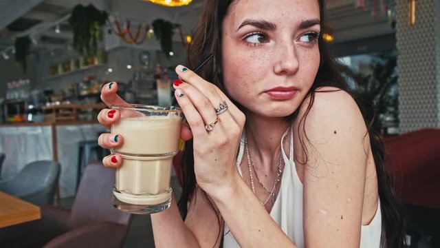 Serious girl drinks coffee in hipster caffeteria