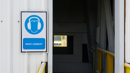 Ear protection sign on blue background on wall infront of door