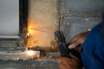 Image of worker welding metal and producing smoke and sparks.
