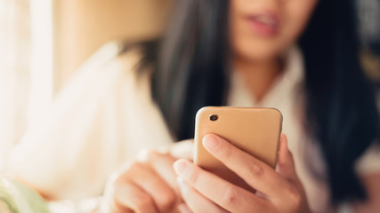 Close up of young woman sitting at cafe with mobile phone. using smart phone at coffee shop. Blurred background and Soft focus.