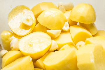 Uncooked garlic potatoes for pickling in deep dish.
