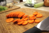 Macro Sliced carrots, vegetable preparation, slicing carrots on wooden board 