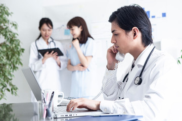 Fototapeta premium 若手男性医師が同僚と電話で話している