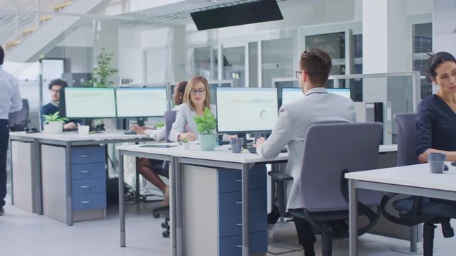 In the Bright Busy Office Rows of Young Professionals Working on Desktop Computers, Talking, Doing Client Support, Communicating with Customers, Monitoring Statistics, Walking Thorugh Hallway