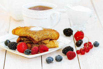 Delicious thin pancakes close up, with fresh blueberries on white wooden background. Sweet Homemade Stack of Pancakes with Butter, fresh forest berries, cream or yogurt with tea in white porcelain Cup