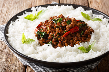 Stir fry basil chicken with chili pepper and soy sauce with a side dish of rice close-up on a plate. horizontal