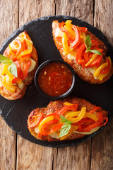 Delicious cayenne chicken breast baked with cheese and bell peppers closeup on a board. Vertical top view