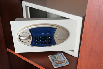 A wad of dollars and an open safe in the closet. Keeping money in a safe place from thieves. The concept of protecting your valuables and money under a code lock.