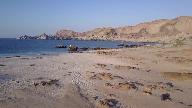 Las Tortolas beach aerial footage at Atacama Desert the sunset ray lights illuminate this amazing and idyllic beach in the middle of the desert, an arid awe landscape crashed by Pacific Ocean waters