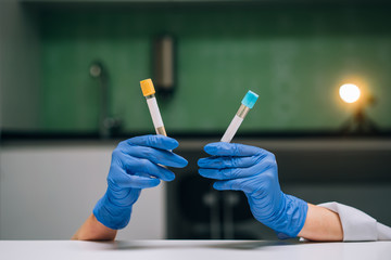 A rubber-gloved hands holds two test tube with the drug