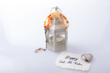 the word EID EL FITR   on torn paper beside lantern and prying beads - obrazy, fototapety, plakaty