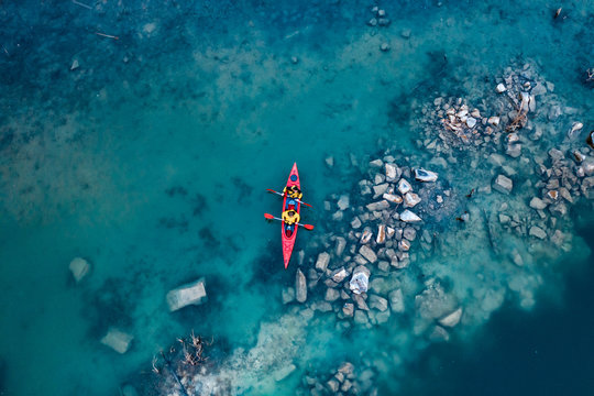 two athletic man floats on a red boat in river