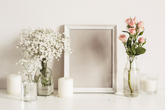 Photo frame, flowers and candles on table wall background. Front view mockup template