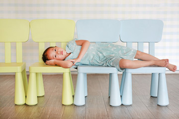 Portrait child preschool girl in a Kindergarten room lying on plastic baby chair. © zilvergolf
