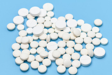 Lots of white pills on a blue background. Pills scattered on a blue background. Medical background. Health, Pharmacy.
