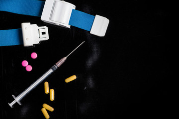 injection syringe with needle pills and plait on dirty black background