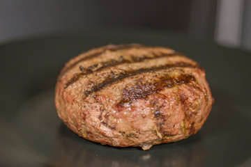 Burger cutlet on a black plate close up