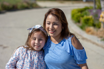 Fototapeta na wymiar Latina Mother and Daughter Smiling and laughing on suburban street