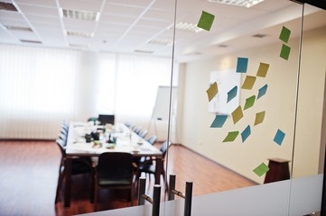 Blank colored sticky note or post note stuck on glass wall at office.