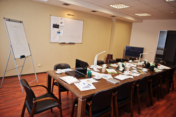 Modern business office interior containing tables and chairs, laptop, camera and office supplies with no employees.