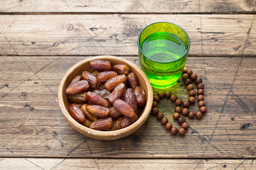 Dried dates fruits and a glass of water on a wooden table. Traditional fast breaking, Muslims evening meal during holy Ramadan