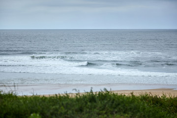 Landscape of French Atlantic coast. Green grass on sandy hill near beach on the shore of  the Bay of Biscay. Silver Coast of France. Ocean water and waves