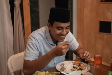 Obraz na płótnie Canvas handsome asian young muslim man eating dinner with family