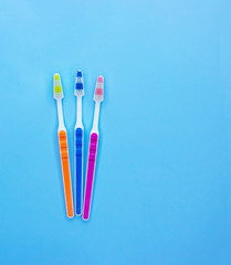 Multi-colored toothbrushes on a blue background with copy space. Flat lay. Top view.