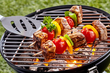 Grilling colorful kebabs over a portable barbecue