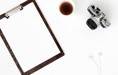 Top view of laptop, old camera, cup of coffee and notebook over white background