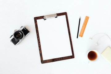 Top view of laptop, old camera, cup of coffee and notebook over white background