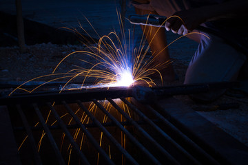 close-up asian welder man working on the metal sculpture at the construction site.