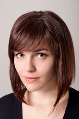 Fototapeta premium Closeup portrait of brown-haired girl with hairstyle and clean skin on a white background.