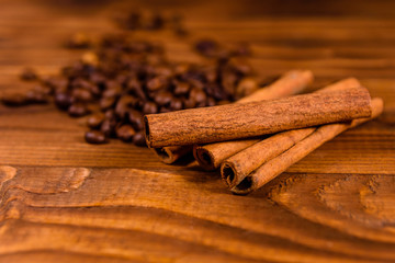 Pile of the coffee beans and cinnamon sticks on wooden table