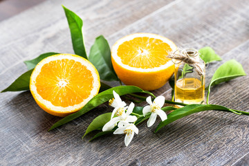 Juicy Orange cut in two parts and neroli, flowers of orange tree, on rustic wood background. The...