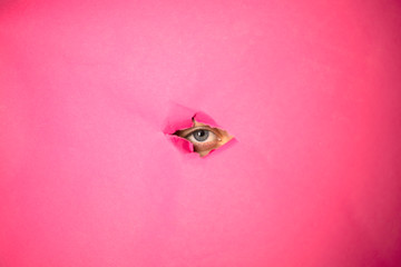 The eye looks through the hole in pink paper